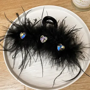 Close-up detail of a black feather hair claw clip with sparkly rhinestone hearts