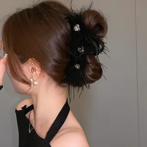 Detail of black feather claw clip with sparkling rhinestone hearts on hair.