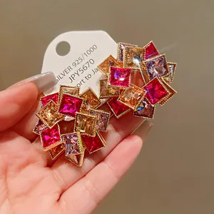 Dettaglio macro di orecchini a fiori geometrici con cristalli rosa e arancio scintillanti