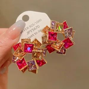 Dettaglio macro di orecchini a fiore con strass quadrati colorati e ago in argento S925