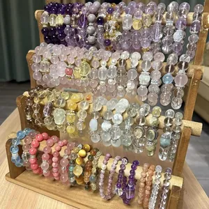 Detailed collection of assorted colorful crystal and gemstone beaded bracelets on wooden stand