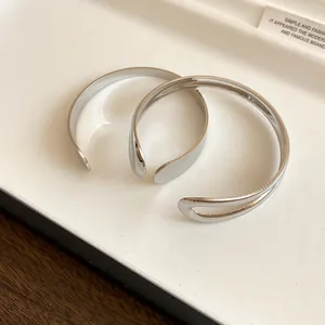 Detail shot of minimalist silver metal open cuff bracelets with teardrop cutout design