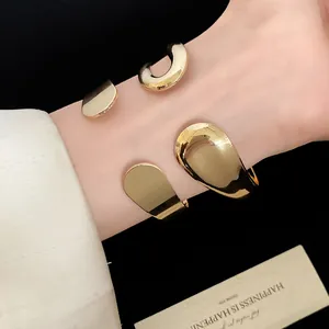 Close-up detail of a vintage gold metallic teardrop open cuff bracelet on wrist.