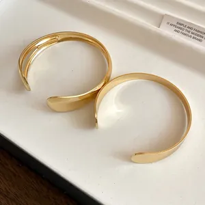 Detailed view of gold-toned open bangles with a polished finish on a white tray.