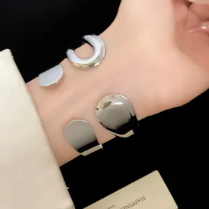 Detailed view of silver metal waterdrop and horseshoe open cuff bracelets