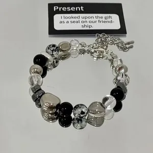 Close-up detail of a glass marble and silver beaded bracelet on a reflective surface.