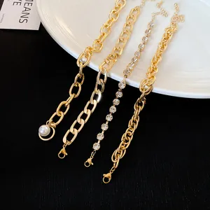 Detail view of four gold-toned stackable bracelets with rhinestones and pearl charm