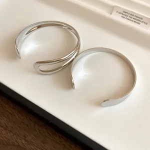 Close-up view of minimalist silver metal open cuff bracelets on a white display tray