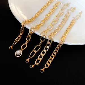 Detail shot of five diverse gold-tone chunky chain bracelets with a pearl charm