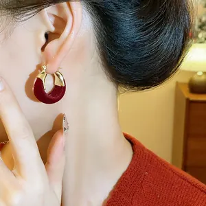 Primo piano di una modella che indossa orecchini a cerchio a U floccati color bordeaux