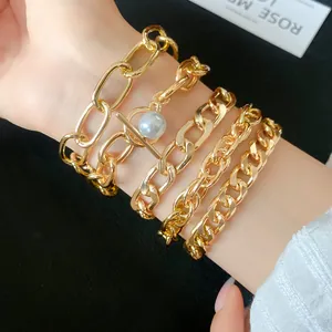 Detailed view of multi-layer gold chunky chain bracelets with a white pearl charm