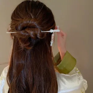 Vue détaillée d'une élégante épingle à cheveux chinoise avec pompon de fleur sur un chignon.