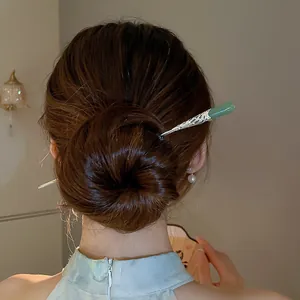 Vue détaillée d'une épingle à cheveux argentée vintage avec pierre verte dans un chignon