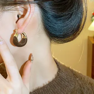 Primo piano di una modella che indossa eleganti orecchini a cerchio in floccato marrone