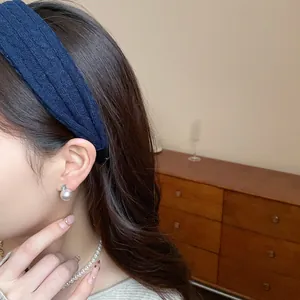 Detail view of navy blue knitted fabric headband showing high-top style on model