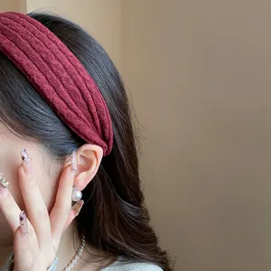Close-up of a burgundy knitted headband on a woman, showing the high-top hair style effect.