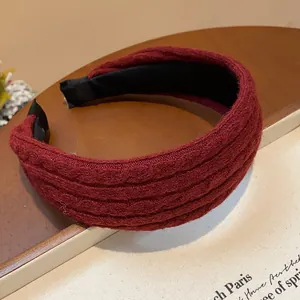 Detailed macro view of burgundy knitted wide headband featuring a soft ribbed fabric texture