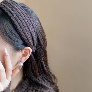 Close-up detail of a dark brown knitted fabric headband on a model for a cozy autumn look