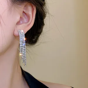 Detail view of sparkly silver rhinestone fringe earrings on a model's ear