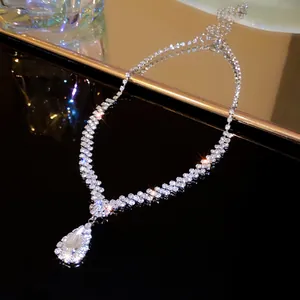 Close-up of elegant V-shaped tassel necklace with sparkling teardrop rhinestone pendant detail.