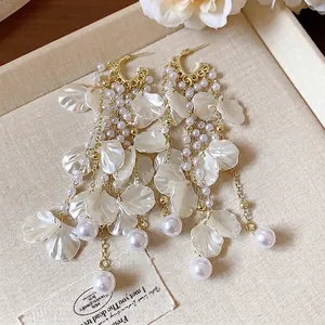 Elegant gold flower petal tassel earrings with white pearls for a luxury resort look.