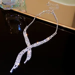 Detailed view of a shimmering rhinestone V-shaped tassel necklace on a dark surface