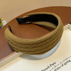 Detailed view of an olive green knitted textured headband on a cozy background