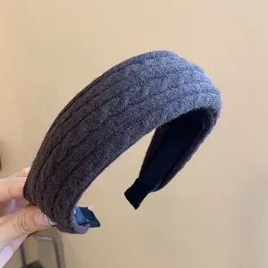 Detailed view of the thick knitted texture on a wide fabric headband.