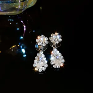 Macro detail of pear-shaped crystal drop earrings with sparkling rhinestone halo.