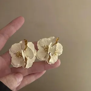 Elegant cream enamel flower stud earrings with golden edges and sparkling rhinestones