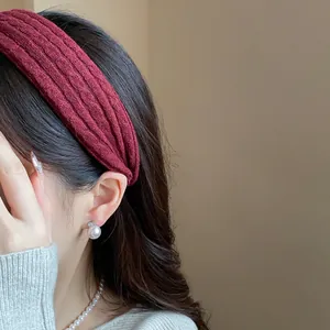 Close-up view of a wine red textured fabric headband styled on a female model.