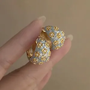Elegant light blue enamel flower earrings with gold rose accents and silver needle