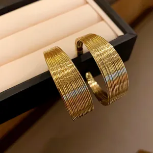 Close-up of elegant gold wide hoop earrings with multi-layer ribbed texture detail