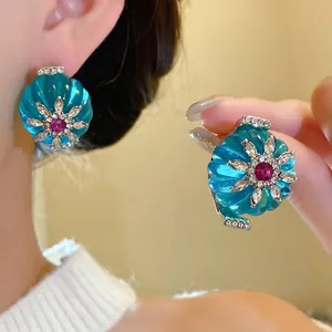 Orecchini vintage in resina blu con cristalli scintillanti e pietra centrale rossa.