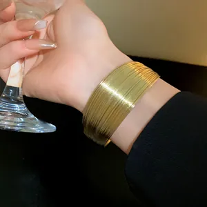 Close-up view of a stylish gold-tone multi-layer wide cuff bracelet worn on a wrist