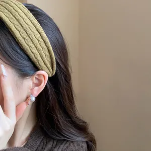 Macro view of olive green knitted headband with textured ribbed design on model