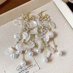 Close-up detail of elegant white floral petal tassel earrings with gold chains and pearl accents