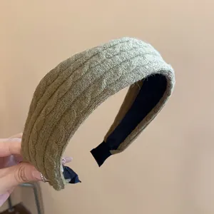 Close-up detail showing the texture of a moss green knitted fabric high crown headband.