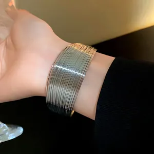 Close-up of a wide multi-layered silver metal cuff bracelet with sleek metallic finish