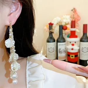 Detailed view of elegant white petal tassel earrings with pearls on an Asian model