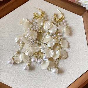 Close-up of white flower petal tassel earrings with elegant pearls and gold chains