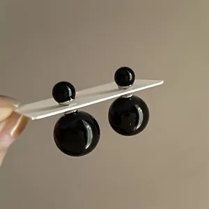 Detailed view of minimalist glossy black double-sided ball stud earrings for women