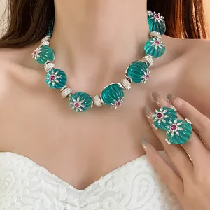 Primo piano della collana vintage in resina turchese e dell'anello con fiori abbinato.