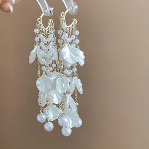 Exquisite detail of long tassel earrings featuring white petals and elegant round pearls