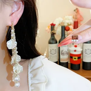 Detail of elegant long floral tassel earring with white petals and pearls on model