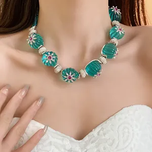 Dettaglio ravvicinato di una collana vintage in resina color petrolio con fiori e cristalli.