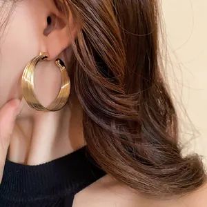 Exquisite close-up detail of golden multi-layered metal hoop earrings worn by a model