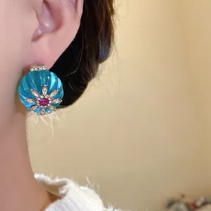 Primo piano di un orecchino a fiore in resina blu vintage con strass scintillanti su modella