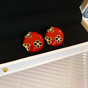 Close-up macro shot of elegant red floral enamel stud earrings with sparkling rhinestones