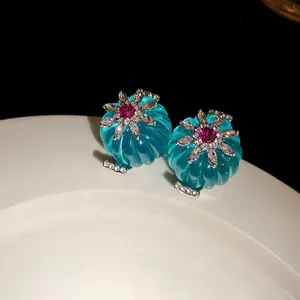 Dettaglio di pendenti vintage in resina color ciano con strass e trama floreale